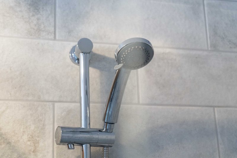 Bathroom shower head and handheld spray mounted on tiled wall