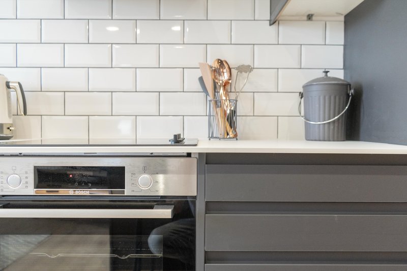 Modern kitchen with white subway tile backsplash, stainless steel oven, and gray cabinetry