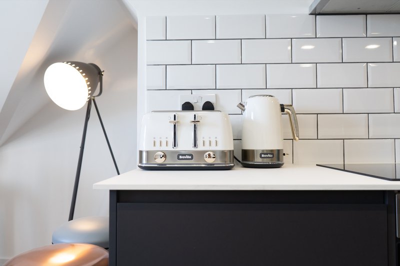 Kitchen counter with white subway tile backsplash, cream toaster, kettle, and tripod lamp