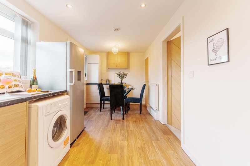 Modern kitchen and dining area with wooden flooring, dining table, chairs, and appliances