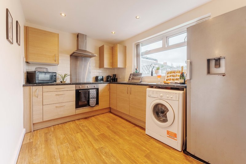 Modern kitchen with wooden cabinets, integrated appliances, and washing machine