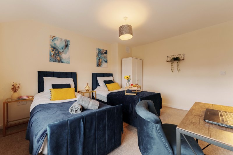Twin bedroom with navy beds, yellow pillows, wooden nightstands and pendant light