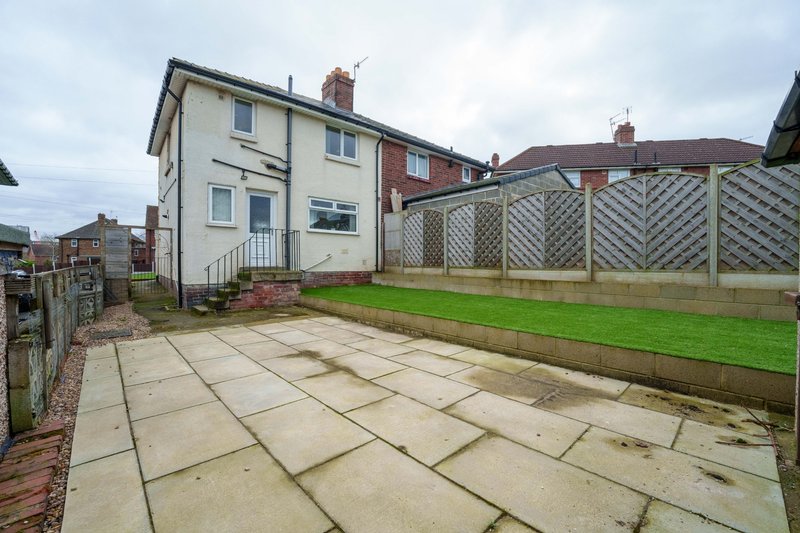 Semi-detached house with patio garden, lattice fence, and neighboring properties visible