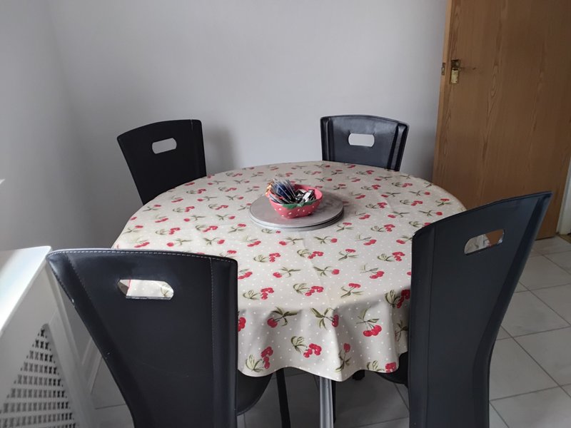 Dining table with floral tablecloth, four black chairs, and decorative bowl centerpiece