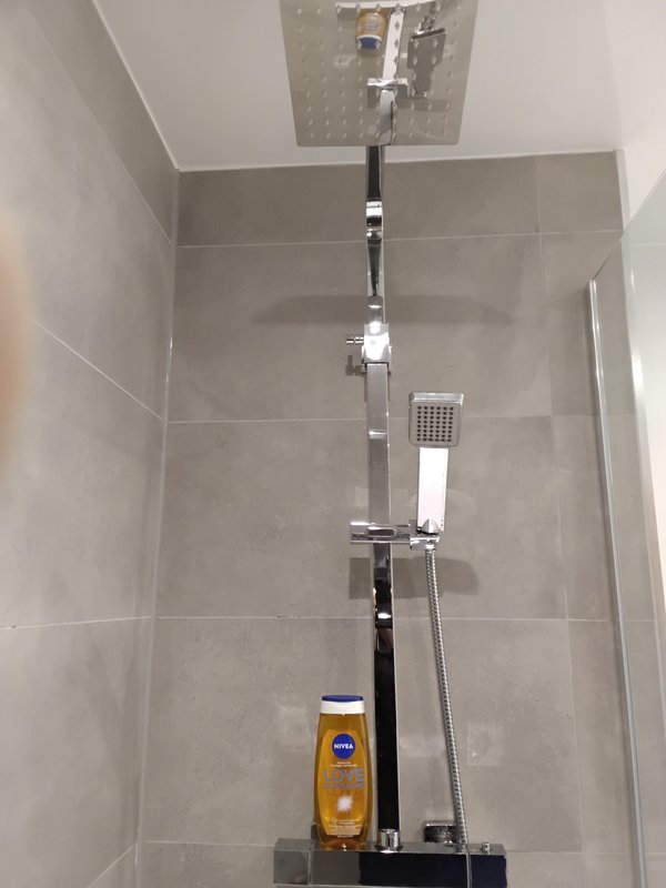 Modern bathroom shower enclosure with chrome fixtures and grey tile walls