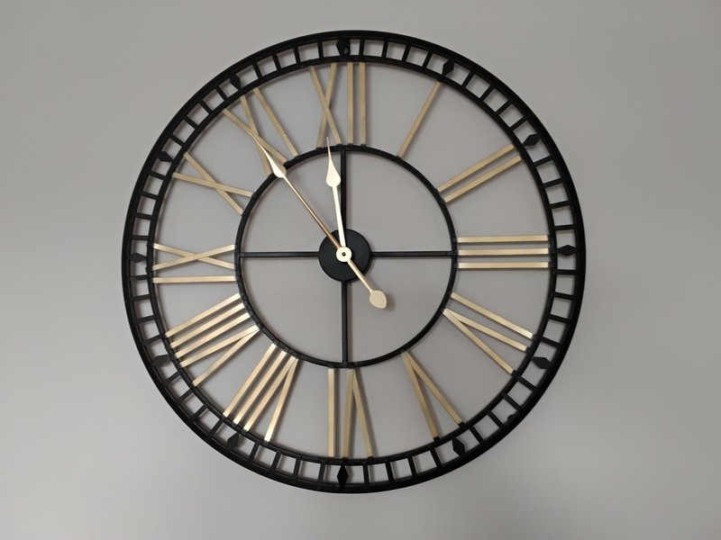 Large decorative wall clock with black metal frame and gold Roman numerals