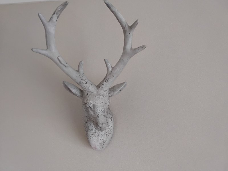 White decorative deer head sculpture mounted on neutral wall