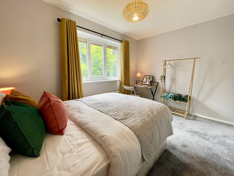 Bright bedroom with double bed, colorful pillows, golden curtains and ceiling light