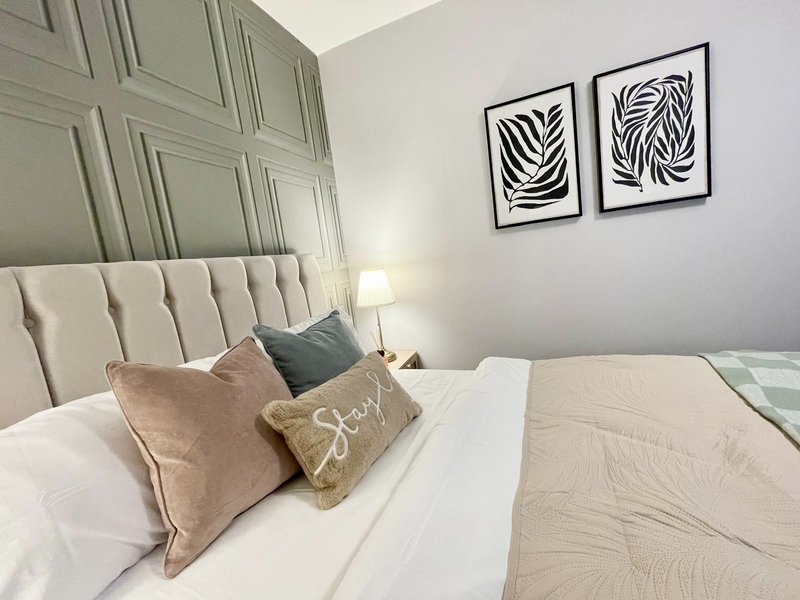 Modern bedroom with upholstered headboard, white bedding, decorative pillows and framed wall art