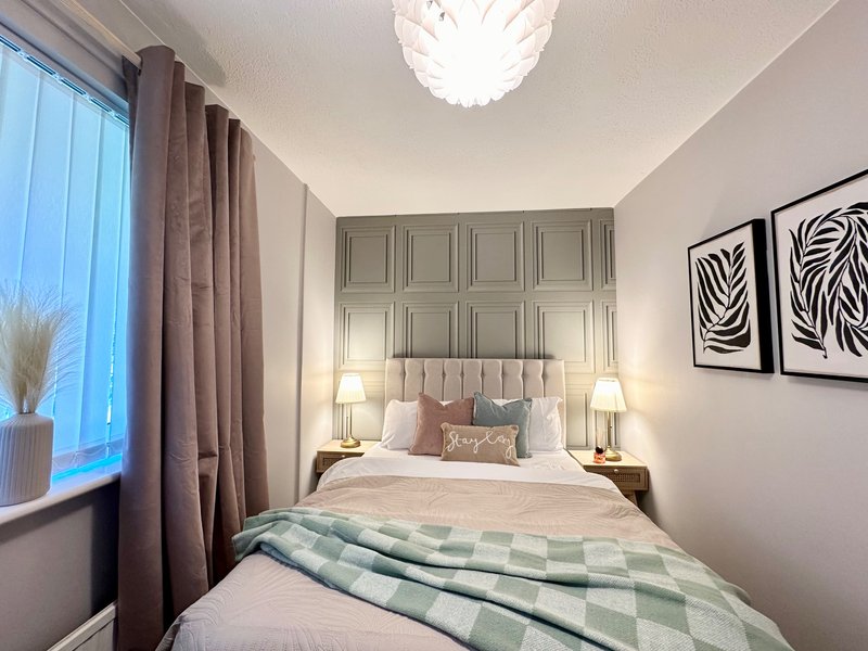 Modern bedroom with double bed, panelled headboard, bedside lamps and abstract wall art