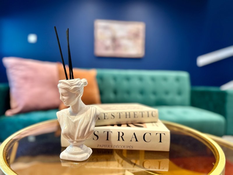 Modern living room with teal sofa, decorative bust, incense holder and styled coffee table