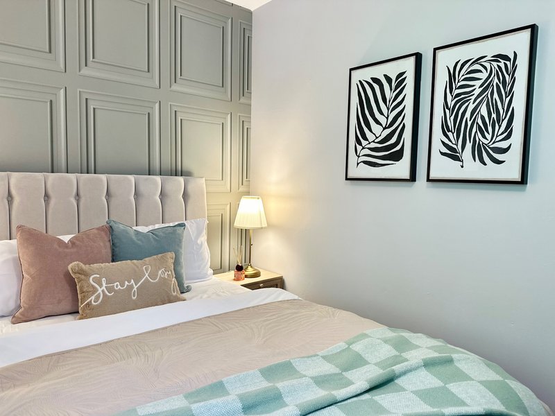 Modern bedroom with upholstered headboard, decorative pillows, bedside lamp and framed wall art