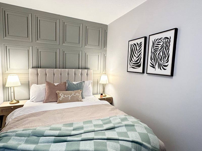 Modern bedroom with upholstered headboard, double bed, bedside lamps, and framed wall art