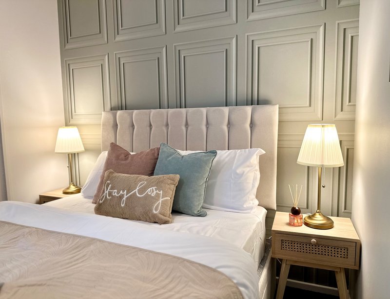 Modern bedroom with upholstered headboard, white bedding, decorative pillows and bedside lamps