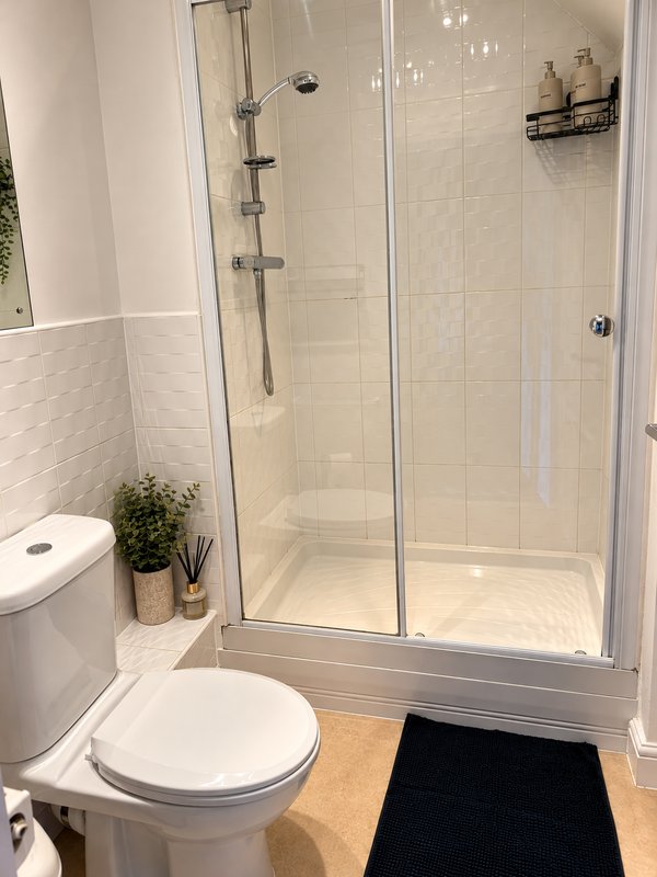 Modern bathroom with white toilet, glass shower enclosure, and cream tile walls