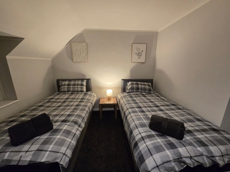 Twin bedroom with checkered bedding, bedside lamp, and framed wall art