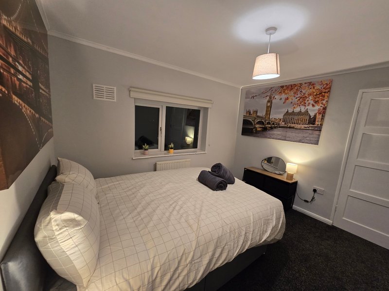 Bedroom with double bed, white bedding, pendant light, framed wall art and dark carpet