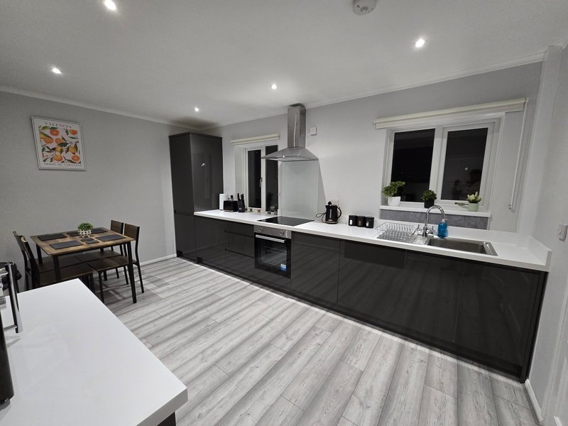 Modern open-plan kitchen and dining area with black cabinetry, white countertops, and striped flooring