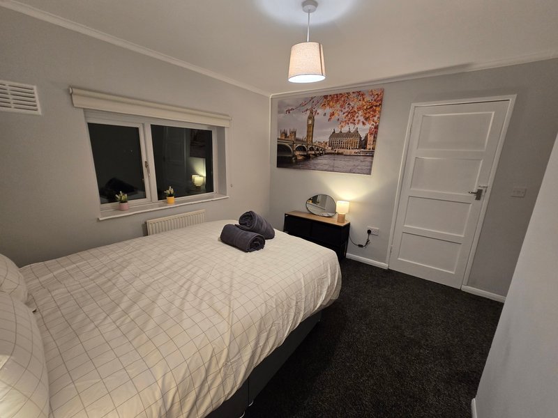 Bedroom with double bed, white bedding, wall art, pendant light and dark carpet