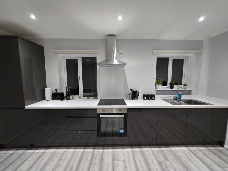 Modern black and white kitchen with central island, stainless steel range hood, and built-in appliances