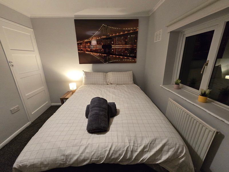 Small bedroom with double bed, bedside lamp, wall art, and window with radiator