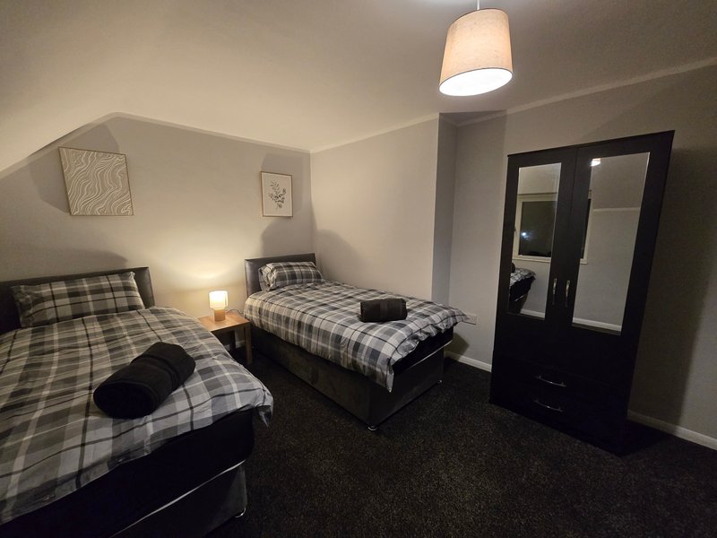 Bedroom with two single beds, checkered bedding, wardrobe and pendant light