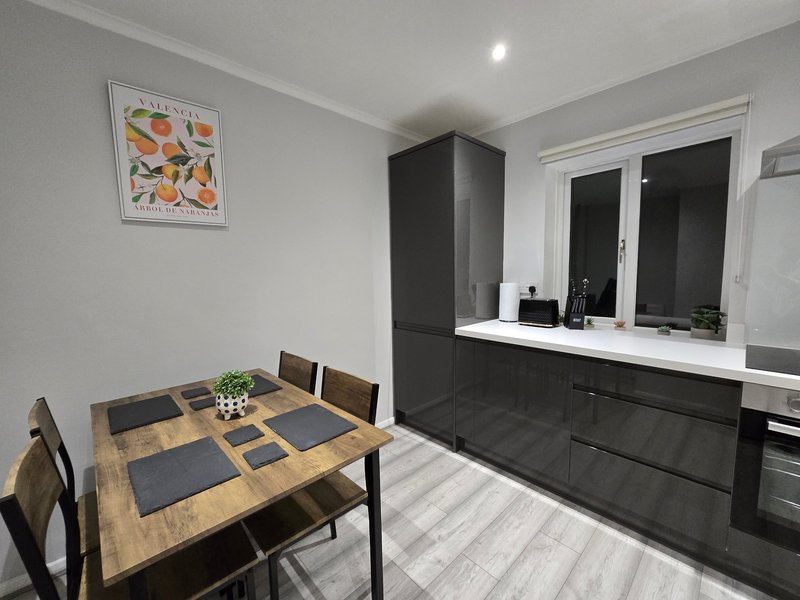 Open-plan kitchen and dining area with wooden table, black chairs, and modern black cabinetry