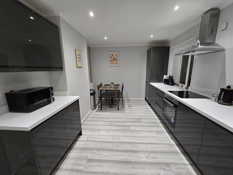 Modern kitchen with dark cabinetry, white countertops, dining table and chairs visible