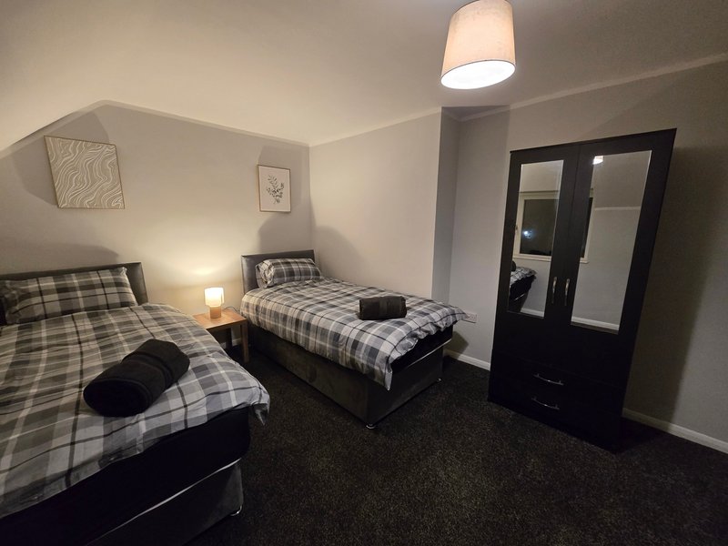 Bedroom with two single beds, checkered bedding, wardrobe and ceiling light