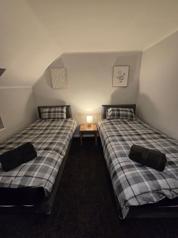 Twin bedroom with two single beds, checkered bedding, bedside table and wall art