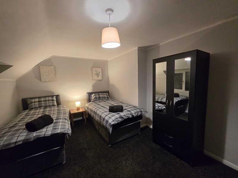 Twin bedroom with two single beds, black wardrobe, pendant light and bedside lamps