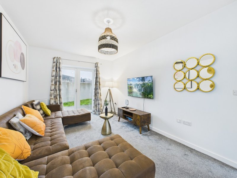 Modern living room with brown sofa, yellow cushions, TV, gold wall decor and glass doors