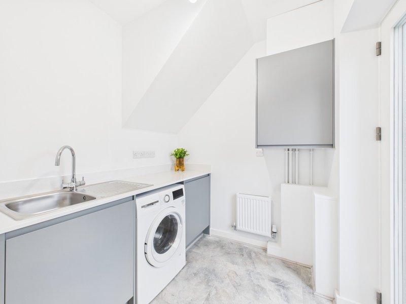 Modern utility room with washing machine, sink, wall-mounted TV, and radiator