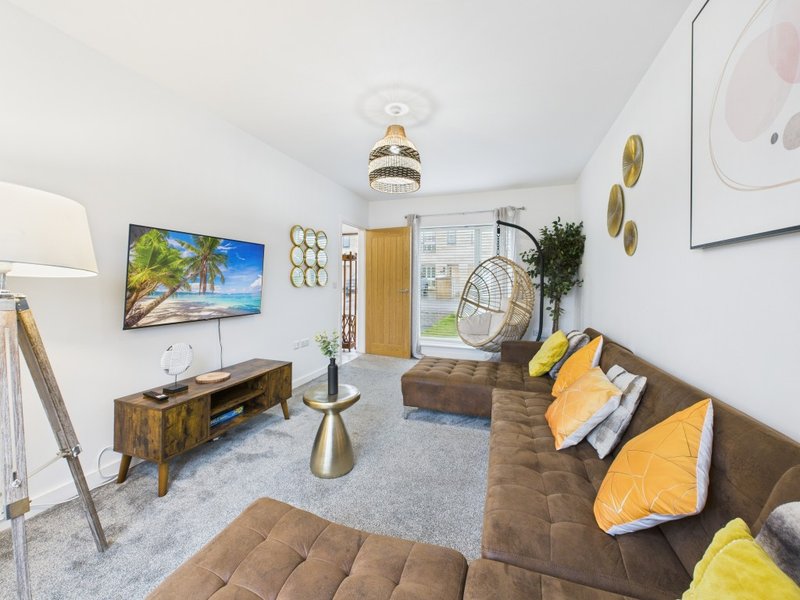 Modern living room with brown sofa, TV, wooden furniture and yellow accent cushions
