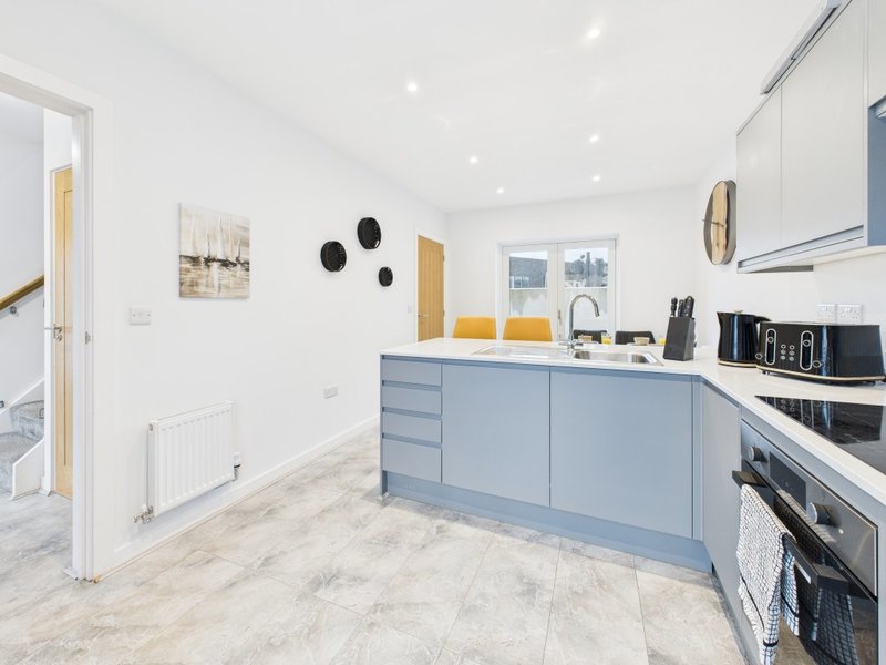 Modern kitchen with blue cabinetry, stainless steel appliances, and marble-effect flooring