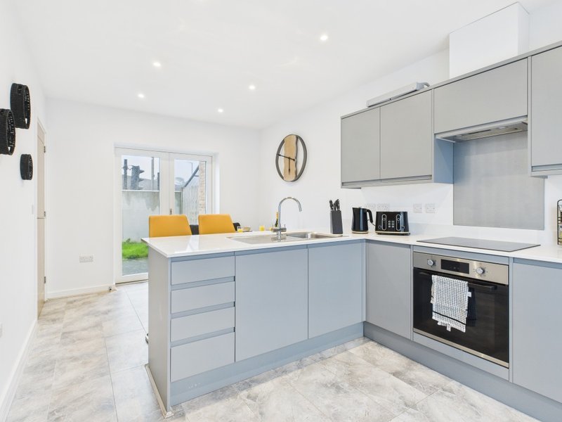 Modern kitchen with light blue cabinetry, white countertops, integrated oven and yellow bar stools