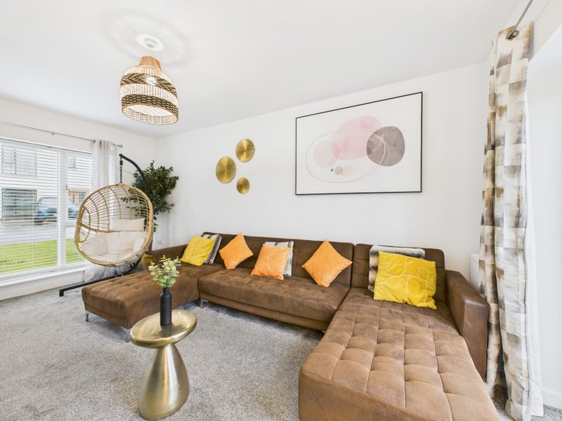 Modern living room with brown sectional sofa, yellow cushions, hanging chair, and abstract wall art