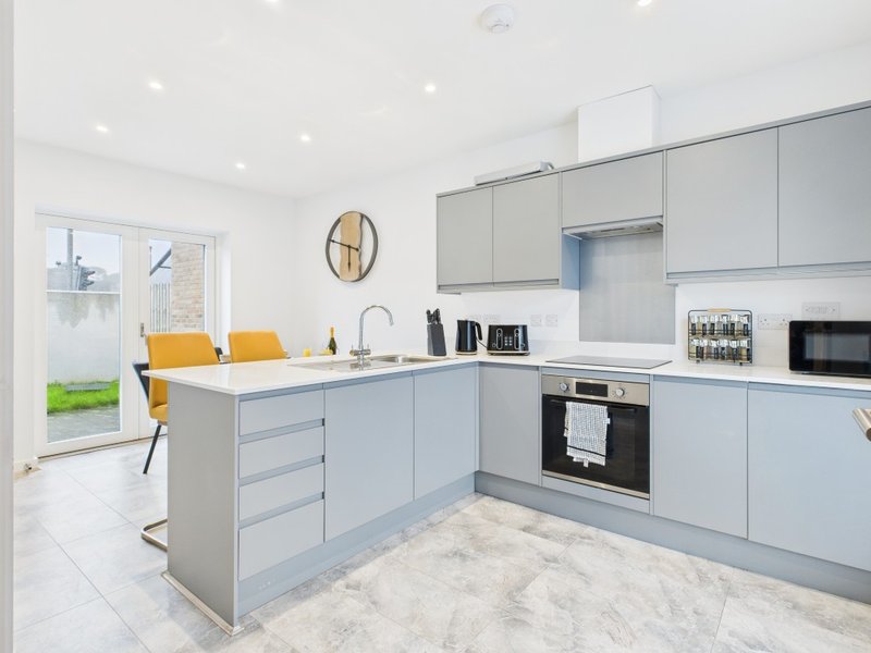 Modern kitchen with gray cabinetry, white marble countertops, island seating, and garden access
