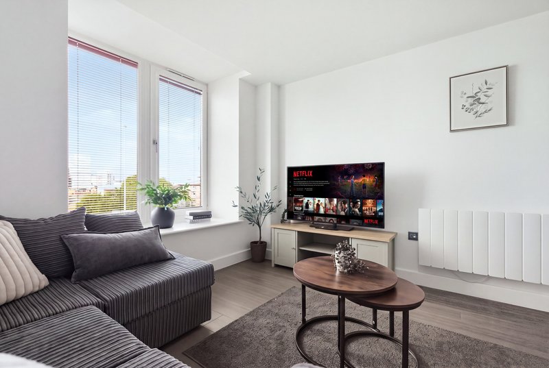 Modern living room with grey sofa, TV, wooden coffee table and large windows