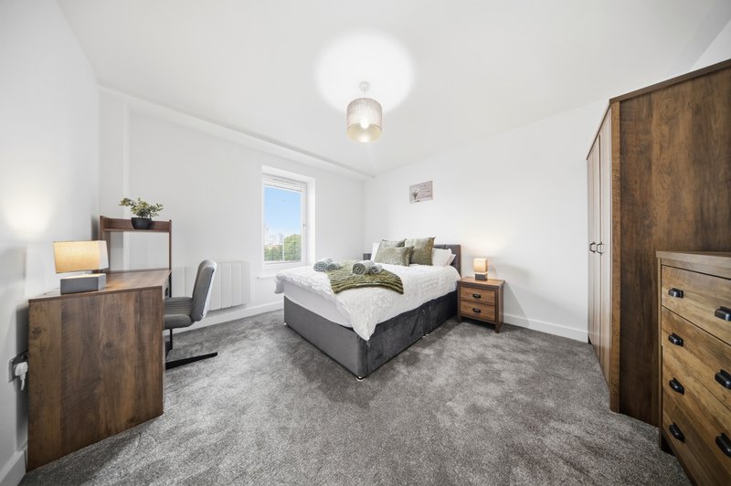 Bright modern bedroom with double bed, wooden furniture, desk area and window with garden view