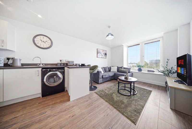 Open-plan kitchen and living room with washing machine, sofa, TV and large windows
