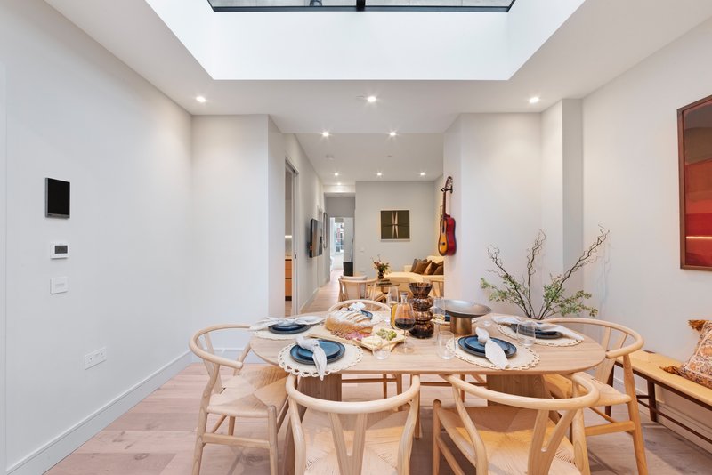 Modern dining room with round wooden table, light wood chairs, and place settings