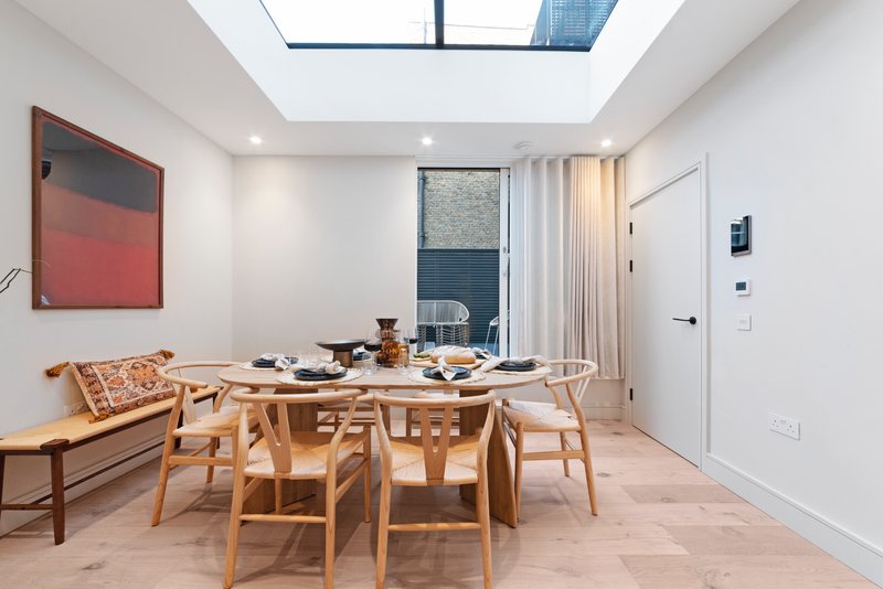 Modern dining room with wooden table, chairs, skylights and minimalist decor