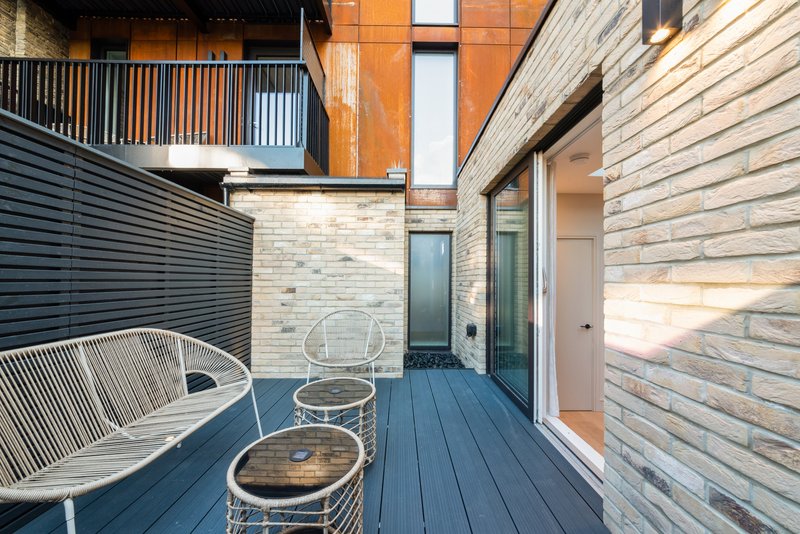 Modern patio area with wooden decking, contemporary seating, and brick exterior walls