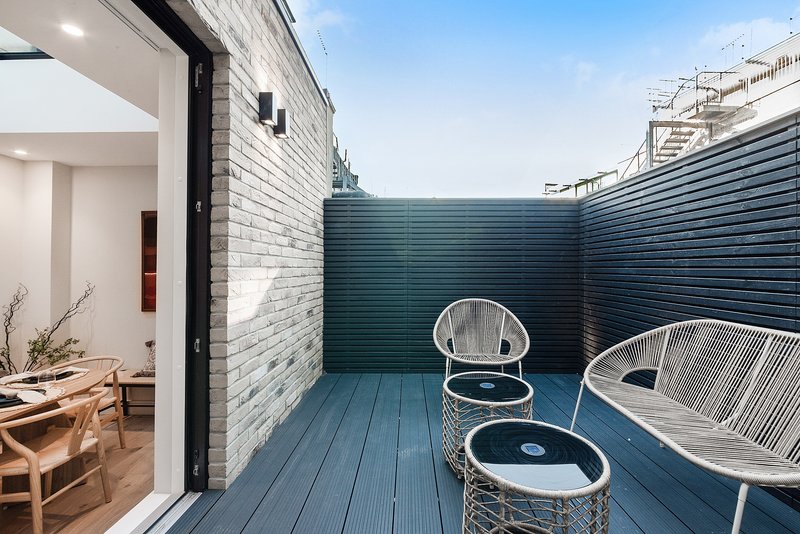 Modern outdoor patio with blue decking, white wicker chairs and small table