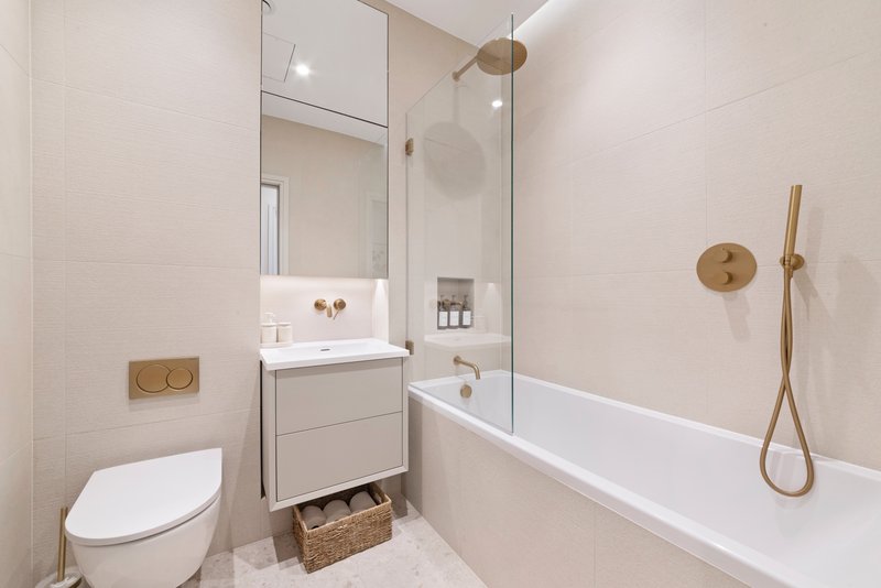 Modern bathroom with white subway tiles, vanity sink, toilet, bathtub and glass shower enclosure