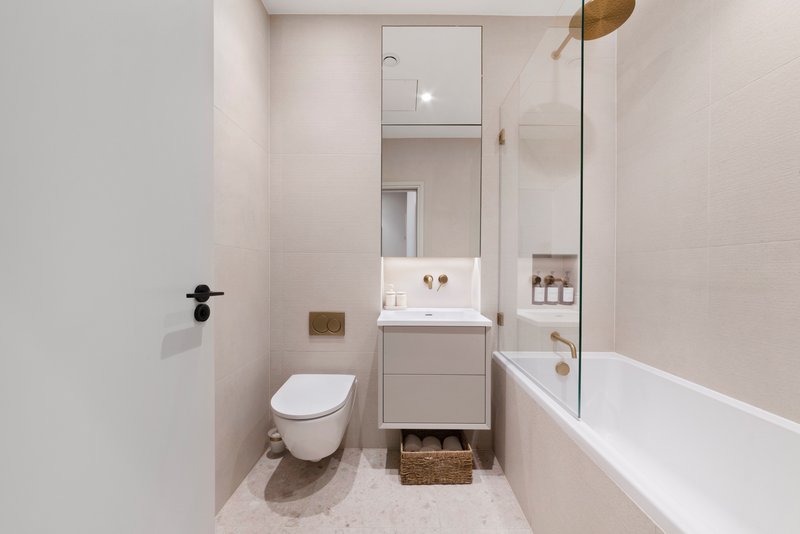 Modern bathroom with white toilet, vanity sink, mirror, bathtub and tiled walls