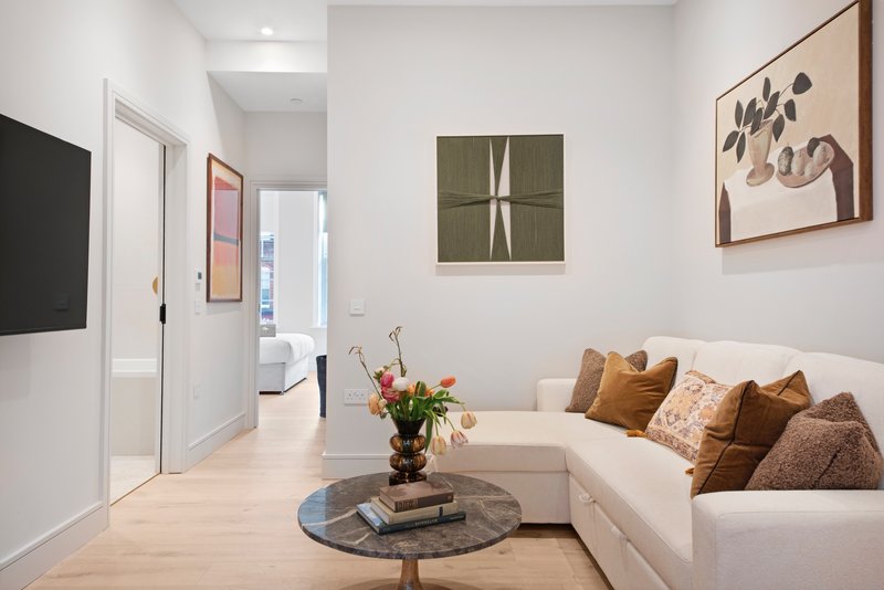 Modern living room with white sofa, round coffee table, wall art and flower arrangement