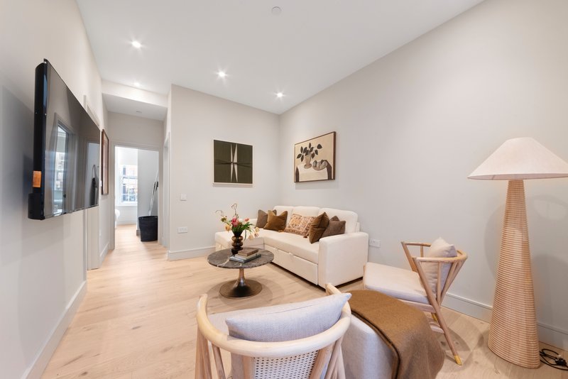 Modern living room with cream sofa, wooden floor, wall-mounted TV, and contemporary furnishings