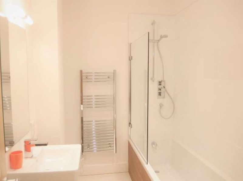Modern bathroom with white sink, heated towel rack, shower enclosure and bath